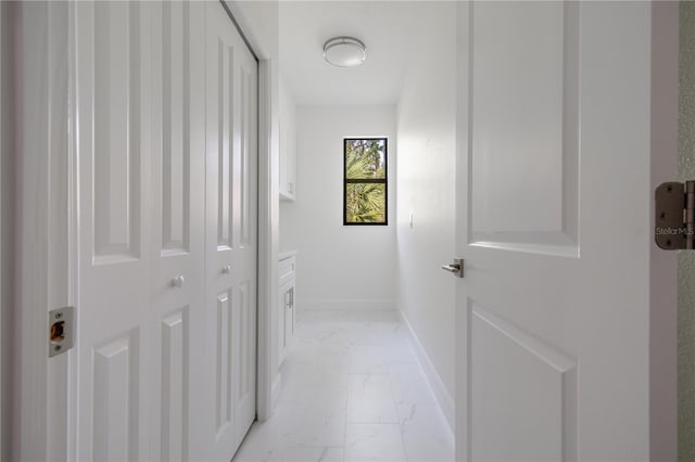 corridor featuring marble finish floor and baseboards