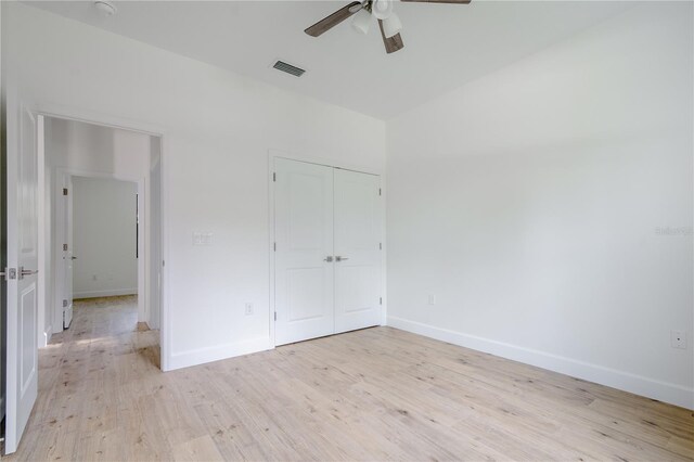 unfurnished bedroom featuring light wood finished floors, baseboards, visible vents, and a closet