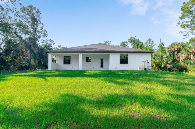 rear view of house with a yard and stucco siding