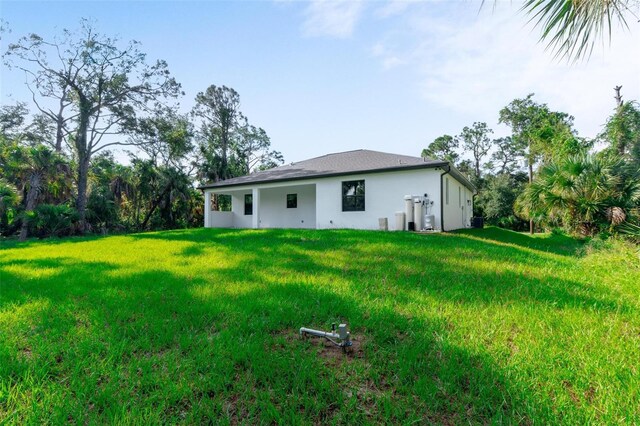 back of property with a lawn and stucco siding