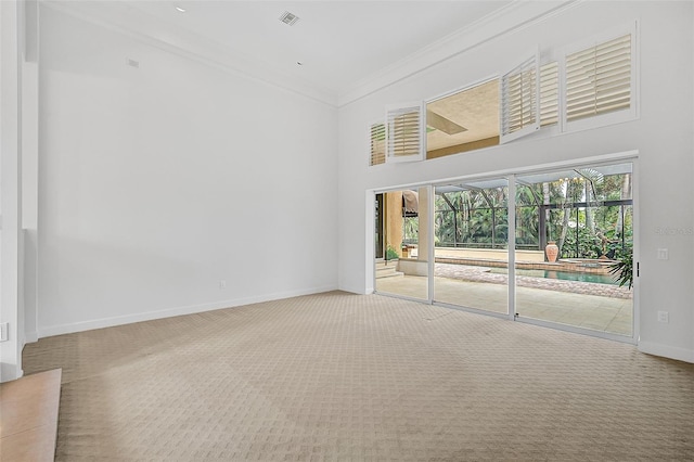 empty room featuring crown molding, a high ceiling, and carpet