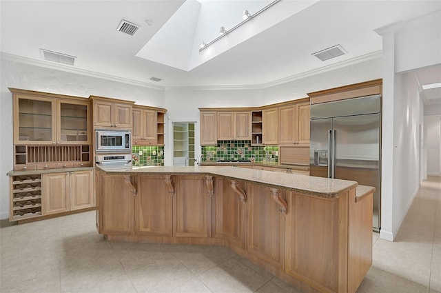 kitchen featuring a kitchen island with sink, built in appliances, light tile patterned floors, and a breakfast bar