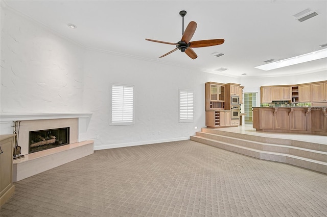 unfurnished living room with a high end fireplace, crown molding, light carpet, and ceiling fan