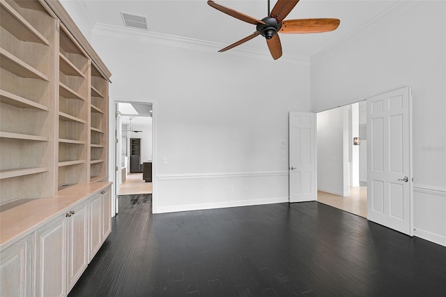 empty room featuring crown molding, dark wood-type flooring, a high ceiling, and ceiling fan