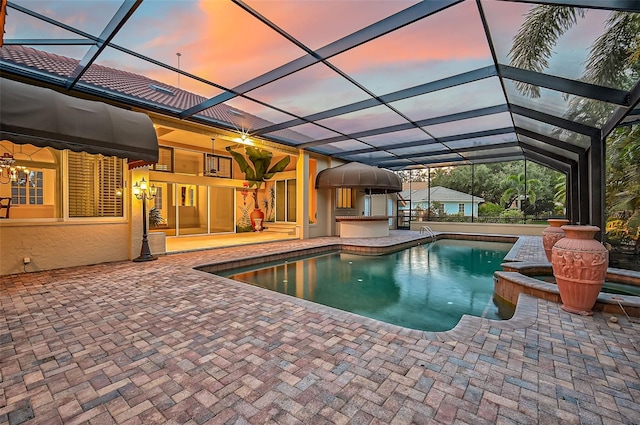 pool at dusk with a lanai, a patio area, and ceiling fan