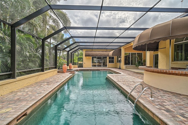 view of pool featuring glass enclosure and a patio