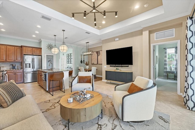 living room with an inviting chandelier, crown molding, sink, a raised ceiling, and light tile patterned flooring