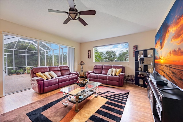 living room with light hardwood / wood-style floors, vaulted ceiling, and ceiling fan