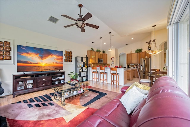 living room featuring ceiling fan with notable chandelier and high vaulted ceiling