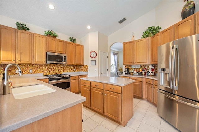 kitchen featuring sink, a center island, lofted ceiling, decorative backsplash, and appliances with stainless steel finishes