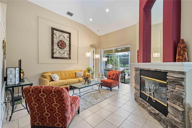 living room featuring light tile patterned flooring, a stone fireplace, and lofted ceiling