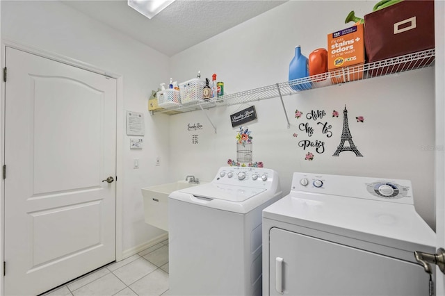 laundry area with washer and clothes dryer, light tile patterned floors, sink, and a textured ceiling