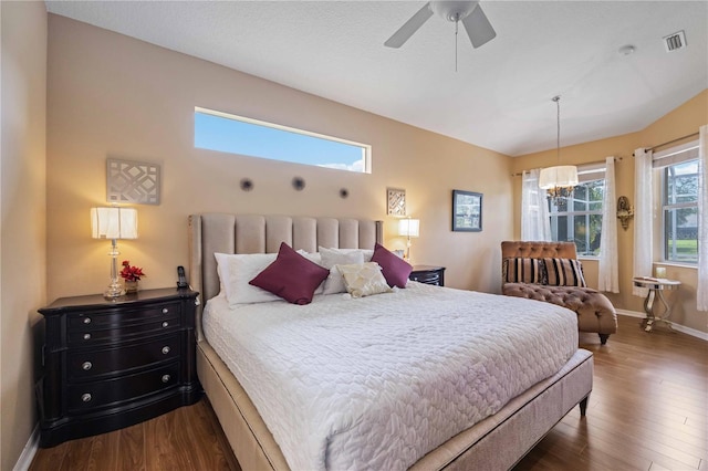 bedroom with multiple windows, dark wood-type flooring, and ceiling fan with notable chandelier