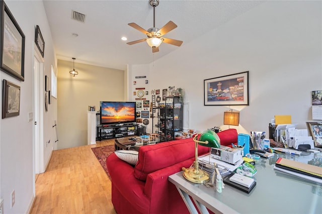 living room with a textured ceiling, light wood-type flooring, and ceiling fan