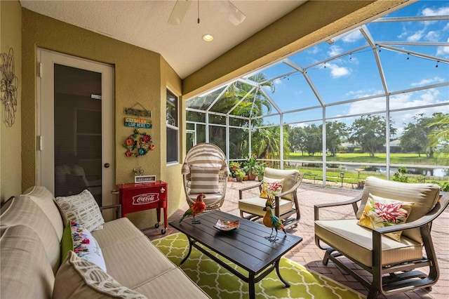 view of patio / terrace featuring glass enclosure, ceiling fan, outdoor lounge area, and a water view