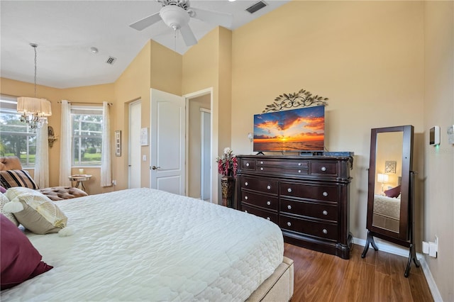 bedroom featuring hardwood / wood-style floors, ceiling fan with notable chandelier, and lofted ceiling