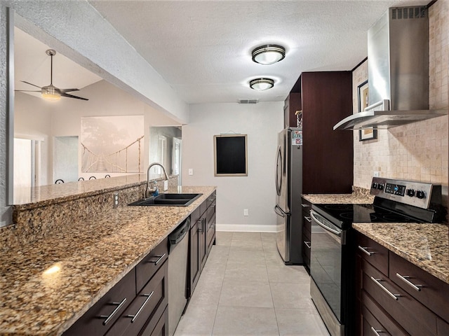 kitchen with sink, light stone countertops, wall chimney range hood, and stainless steel appliances