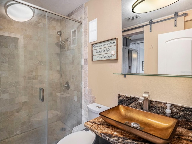 bathroom featuring a shower with door, toilet, a textured ceiling, and vanity