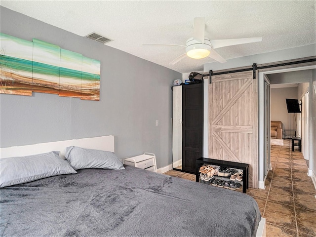 bedroom with a barn door, a textured ceiling, and ceiling fan