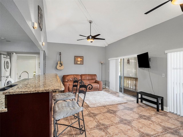 living room featuring lofted ceiling, ceiling fan, stacked washer and dryer, and a wealth of natural light