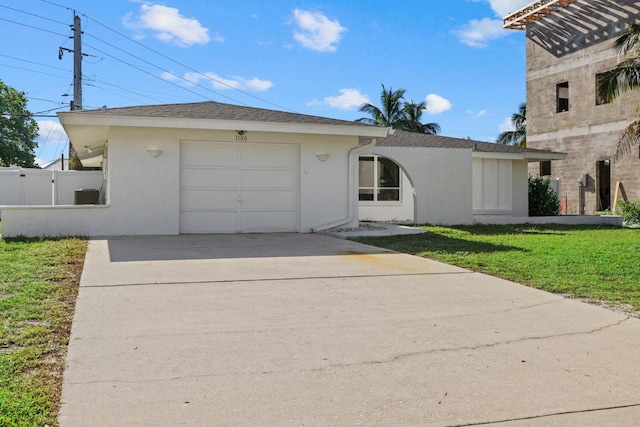 view of front of property with a garage, fence, driveway, stucco siding, and a front yard