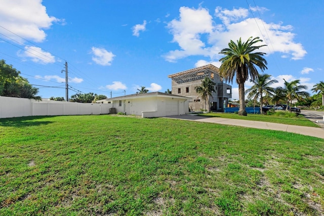 view of yard featuring driveway, a garage, and fence