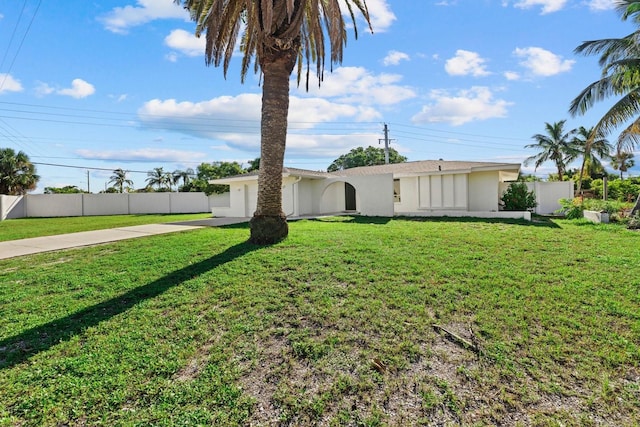 view of front of house with concrete driveway, an attached garage, fence, a front lawn, and stucco siding