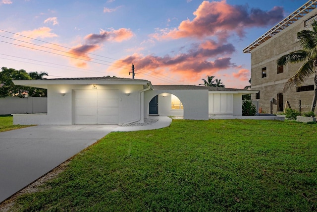 view of front of home with concrete driveway, a front lawn, an attached garage, and stucco siding