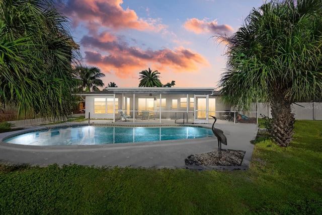 pool at dusk with a yard and a patio