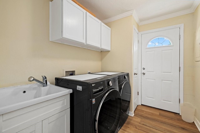 washroom with cabinet space, light wood-style flooring, independent washer and dryer, crown molding, and a sink