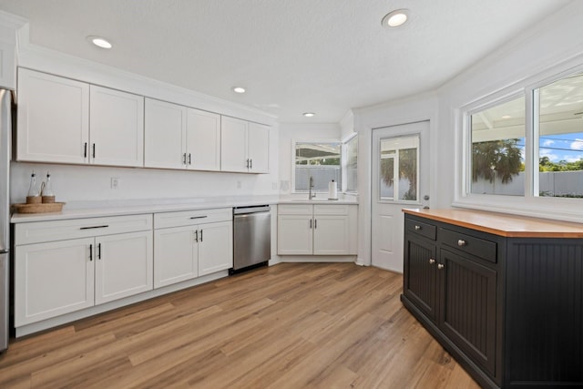 kitchen featuring light wood-type flooring, white cabinetry, a wealth of natural light, and stainless steel dishwasher