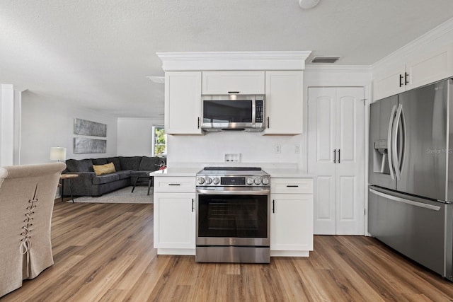 kitchen with hardwood / wood-style floors, appliances with stainless steel finishes, crown molding, and white cabinets