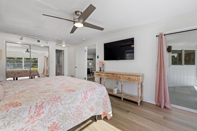 bedroom featuring a textured ceiling, wood-type flooring, rail lighting, ceiling fan, and ornamental molding