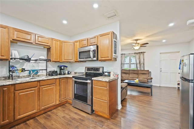 kitchen featuring light stone counters, hardwood / wood-style floors, stainless steel appliances, and ceiling fan