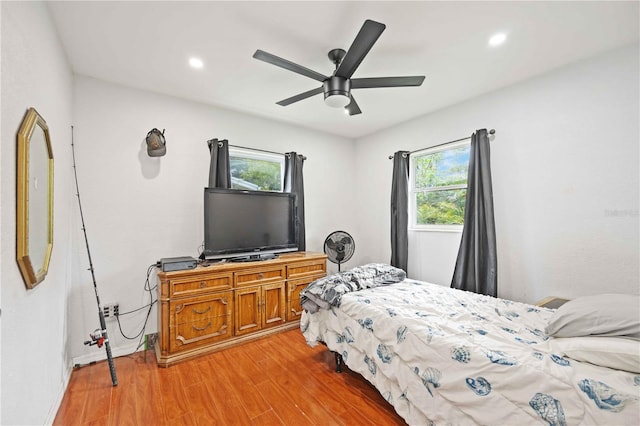 bedroom with multiple windows, wood-type flooring, and ceiling fan