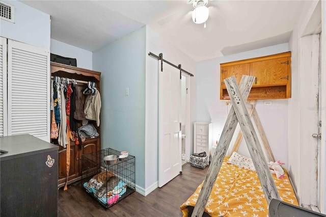 bedroom featuring a barn door, ceiling fan, a closet, and dark hardwood / wood-style flooring