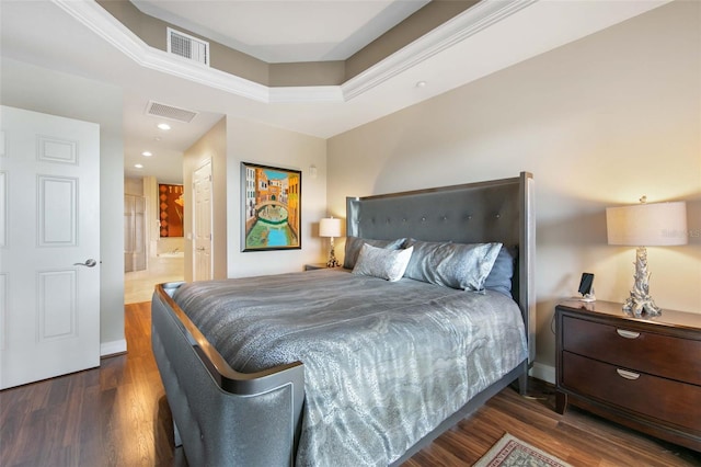 bedroom featuring ensuite bathroom, wood finished floors, visible vents, and baseboards