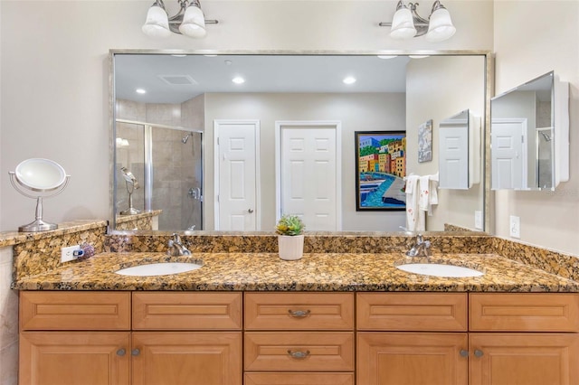 full bathroom featuring visible vents, a sink, a shower stall, and double vanity