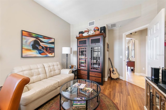 living room with visible vents, baseboards, and wood finished floors