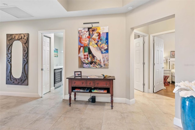 hallway with wine cooler, baseboards, and light tile patterned flooring