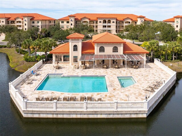 rear view of property featuring a water view, a patio area, fence, a community pool, and a tiled roof