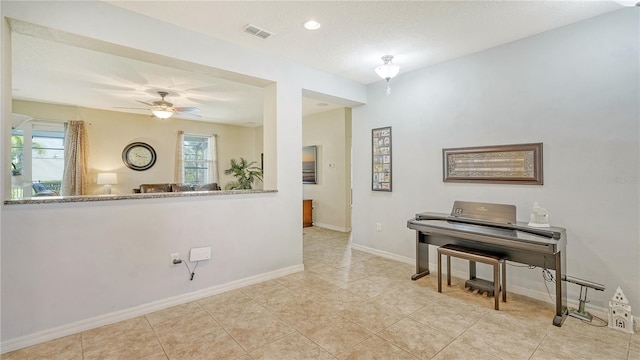 misc room with a textured ceiling, ceiling fan, and light tile patterned floors