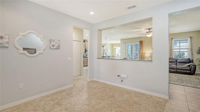 tiled empty room featuring ceiling fan and a textured ceiling