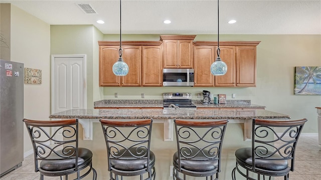 kitchen featuring an island with sink, a breakfast bar area, and appliances with stainless steel finishes