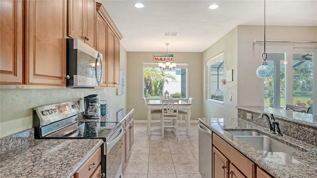 kitchen with stainless steel appliances, stone countertops, a notable chandelier, sink, and pendant lighting