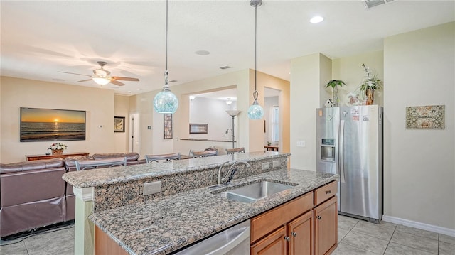 kitchen with a kitchen island with sink, stone counters, sink, ceiling fan, and appliances with stainless steel finishes