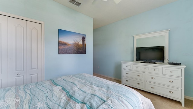 bedroom featuring light colored carpet, ceiling fan, and a closet