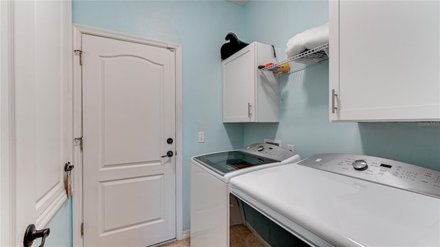 clothes washing area with washer and dryer and cabinets