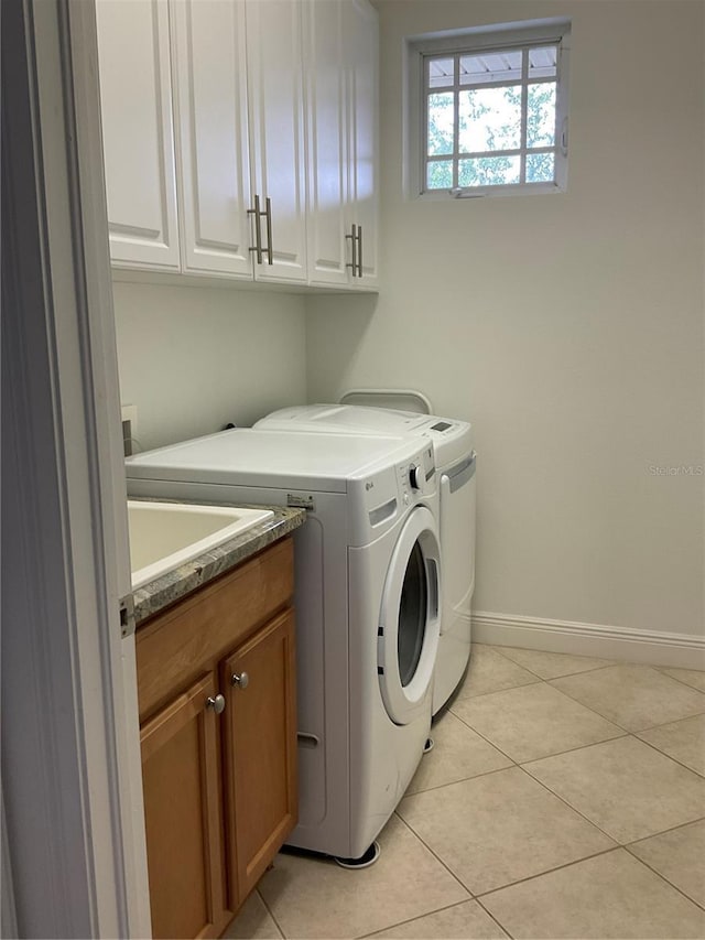 washroom featuring washer and dryer, cabinet space, baseboards, and light tile patterned flooring