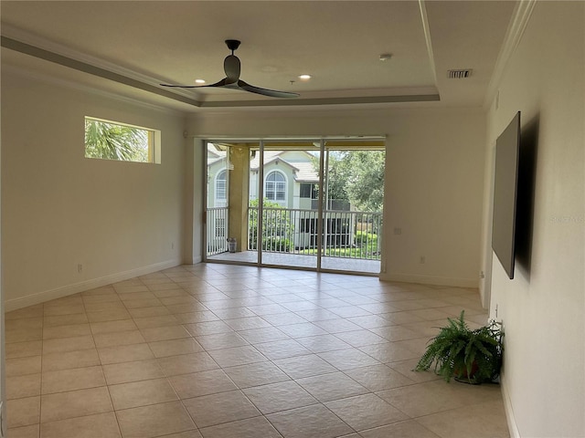 empty room featuring visible vents, ornamental molding, a raised ceiling, and a wealth of natural light